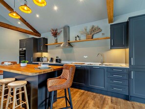 A modern kitchen with dark cabinets, a wooden island, and pendant lighting.