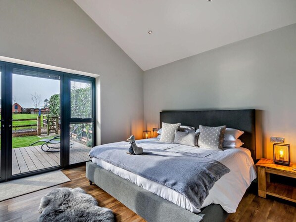 A bedroom with a bed, a nightstand, a lamp, and a view through a sliding door to an outdoor area.