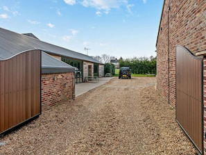 A gravel driveway leading to a building with a sloped roof and a brick wall.
