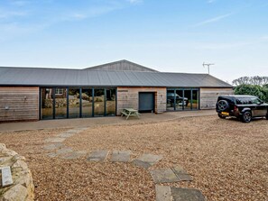 A modern building with a gravel driveway and a parked vehicle.
