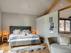 A bedroom with a large bed, bedside tables, a sofa, and a view of a building through a window.