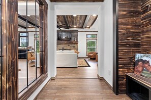 Un interior espacioso con suelo de madera, chimenea y un ventanal grande.
