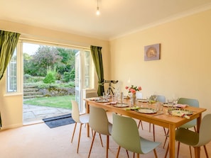 A dining area with a table set for six, a tripod, and a vase of flowers. - 4 Bed in Dorchester (oc-89788) (Corscombe)