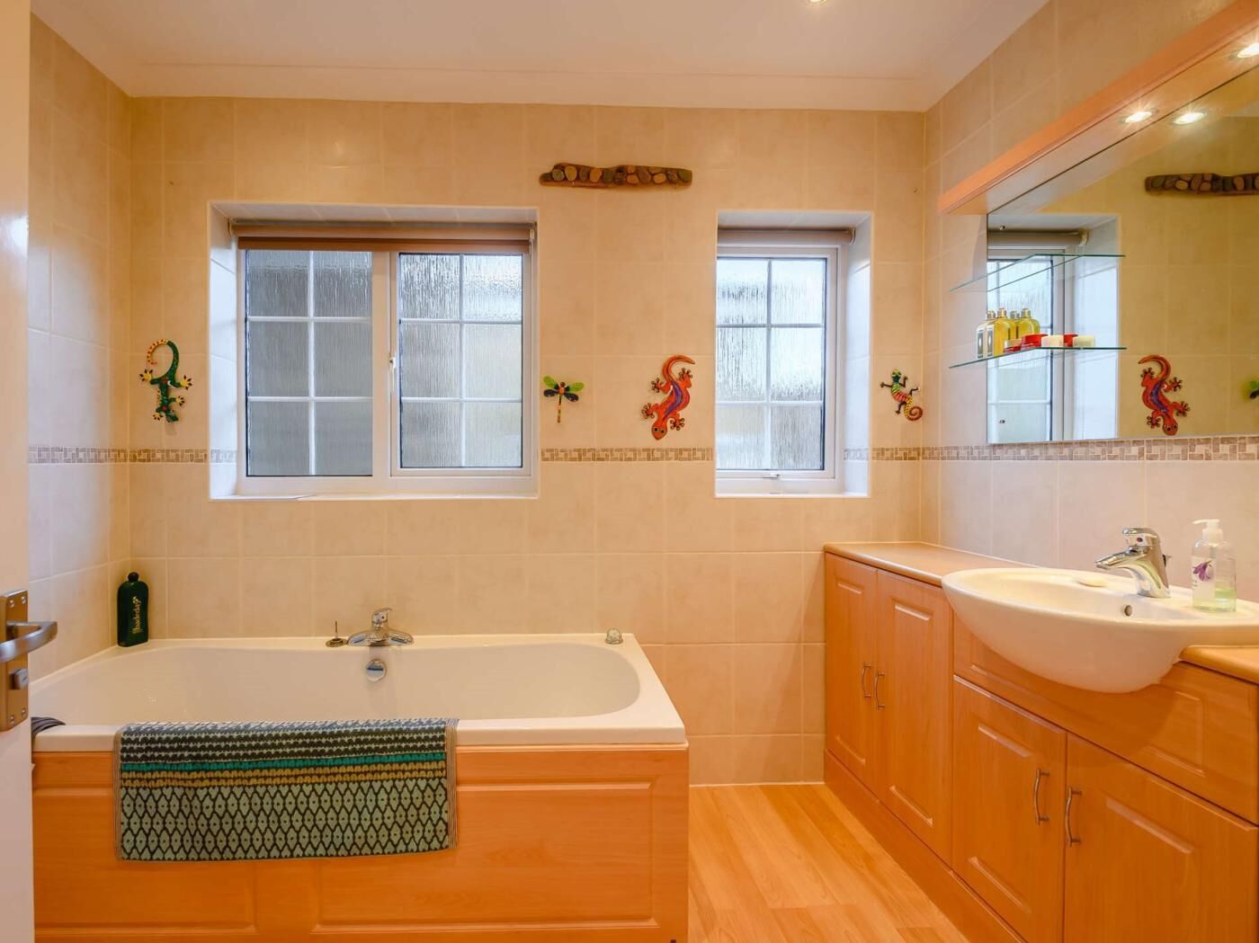 A bathroom with a bathtub, a sink, and two windows.