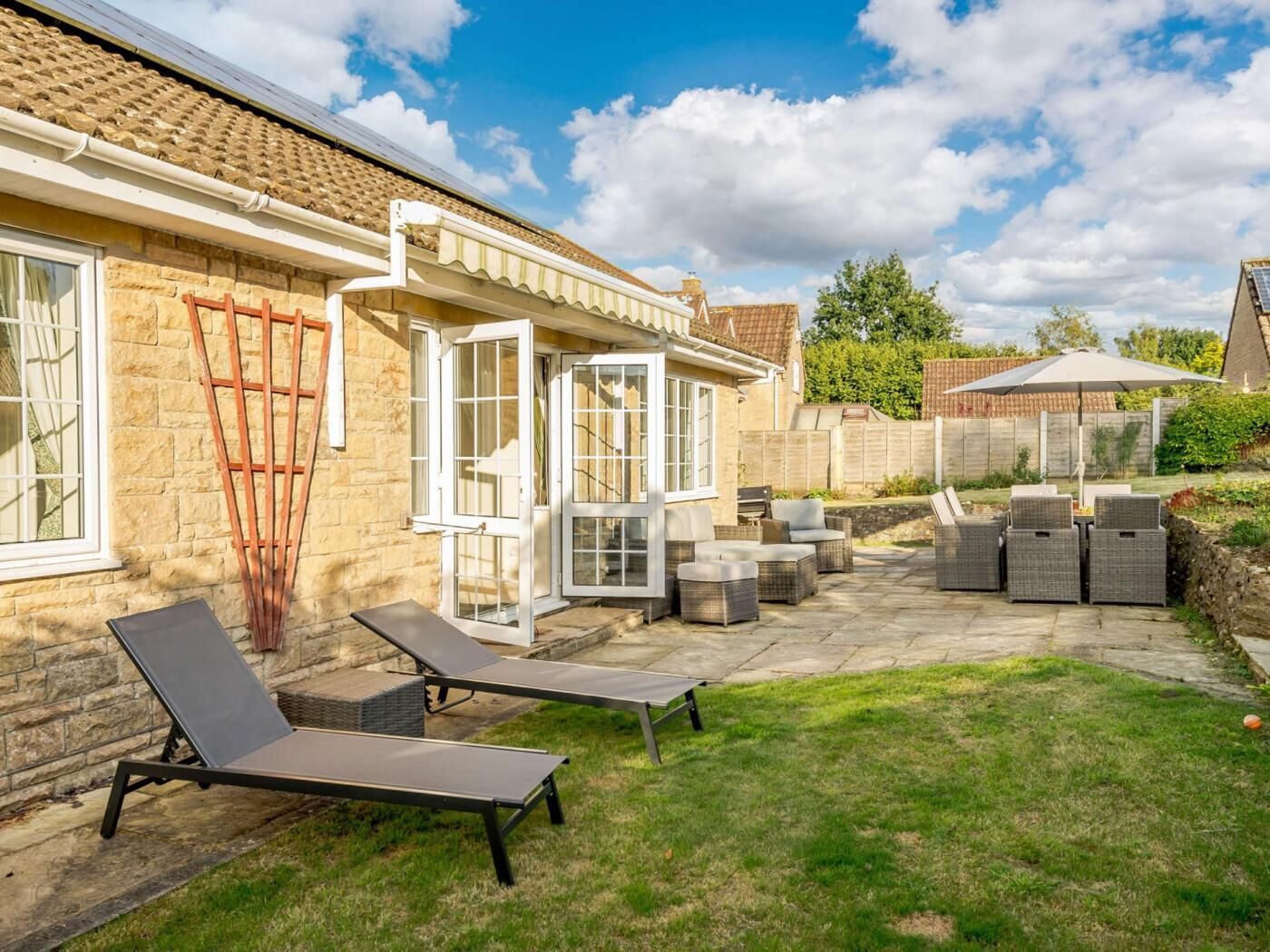 Une terrasse avec des meubles d’extérieur, un espace salon abrité et une vue sur le jardin arrière.