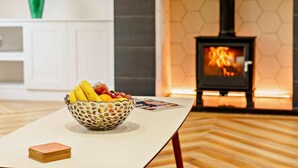 Una habitación con una mesa blanca, un cuenco de fruta, una chimenea y un revestimiento mural con patrón hexagonal.
