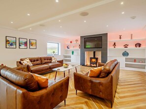 A modern living room with leather sofas, a flat-screen TV, a fireplace, and decorative shelves. - 4 Bed in Penrith (oc-89957) (Shap)
