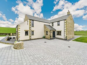 A two-story stone house with a paved courtyard, a stone fireplace, and a view of the surrounding landscape. - 4 Bed in Penrith (oc-89957) (Shap)