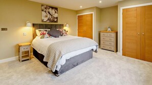 Un dormitorio con cama, mesitas de noche, cómoda y armario.