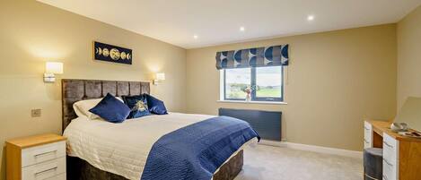 A bedroom with a bed, bedside tables, a desk, and a window with a view.