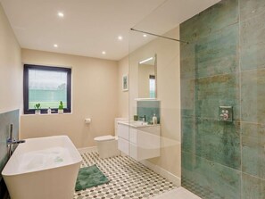 A modern bathroom with a freestanding bathtub, a toilet, a sink, and a shower area. - 4 Bed in Penrith (oc-89957) (Shap)