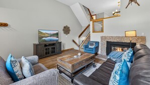 A living room with a sofa, a television, a fireplace, and a staircase. - Cedars Retreat - Walk to Main St & Trails & Pool (Breckenridge)