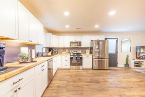 Une cuisine moderne avec des armoires blanches, des appareils en acier inoxydable et un plan de travail en bois.