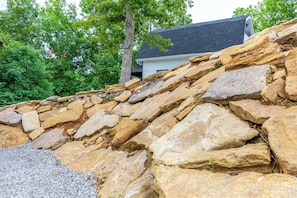 Un muro de piedra con una casa al fondo.