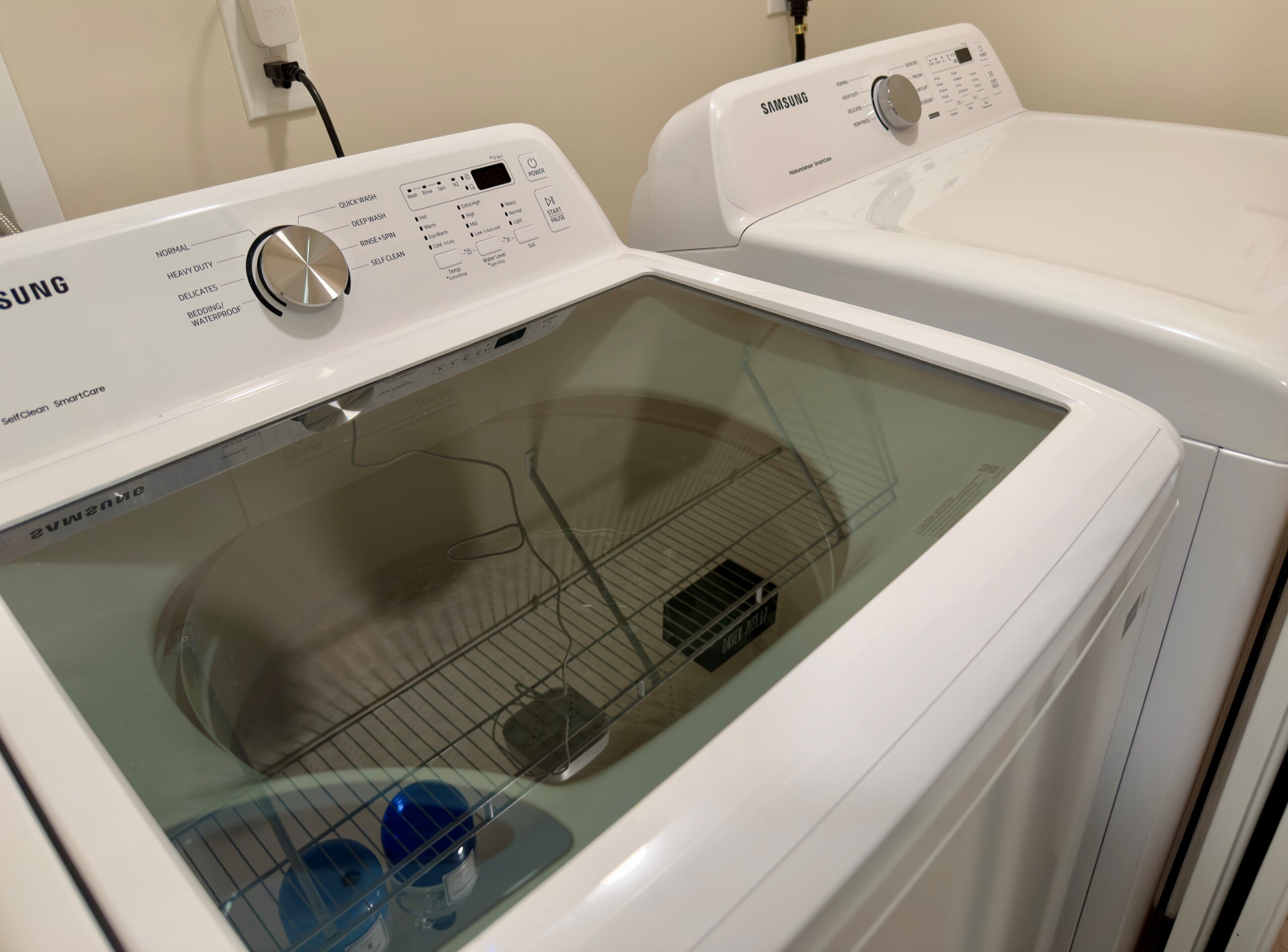 A Samsung self-cleaning smart care washing machine with a control panel and a transparent door.