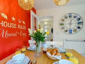 A dining area with a red wall, a wall clock, and a table set for breakfast. - 3 Bed in Narberth (oc-89627) (Templeton)
