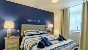 A hotel room with a bed, two bedside tables with lamps, a wall with a decorative phrase, and a window with curtains. - 3 Bed in Narberth (oc-89627) (Templeton)