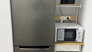 A compact kitchenette with a stainless steel refrigerator, a microwave, and a toaster on a wooden shelf. - Apartment in Amer (Amer)