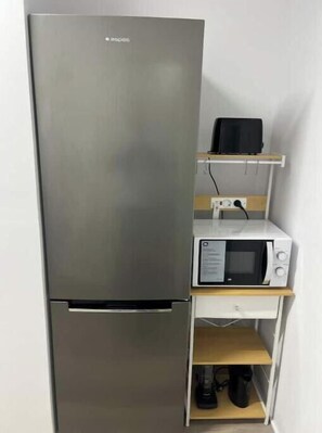 A compact kitchenette with a stainless steel refrigerator, a microwave, and a toaster on a wooden shelf. - Apartment in Amer (Amer)