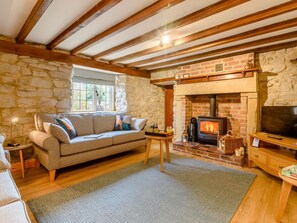 A cozy living room with a stone wall, a fireplace, a sofa, and a television. - 3 Bed in Ashbourne (oc-89740) (Bradbourne)