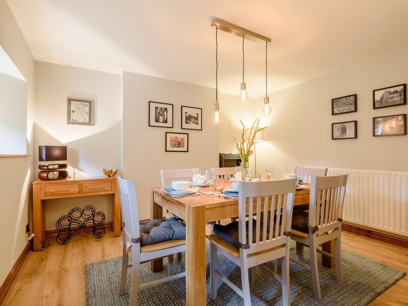 A dining area with a wooden table, chairs, and hanging light fixtures.