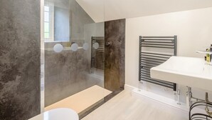 Ein modernes Badezimmer mit einer Duschkabine aus Glas, einem weißen Waschbecken und einem Handtuchhalter.