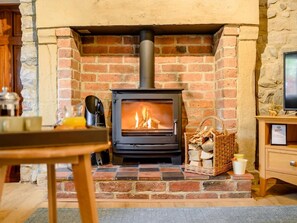 A wood-burning stove in a brick fireplace with a television on a wooden stand to the right. - 3 Bed in Ashbourne (oc-89740) (Bradbourne)