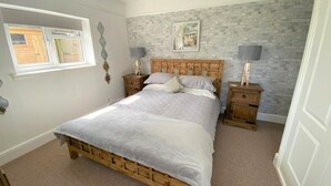 Un dormitorio con una cama de madera, dos mesitas de noche, un ventanal y una pared con diseño de ladrillo.