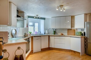 A modern kitchen with white cabinetry, a wooden countertop, and a built-in dishwasher. - 3 Bed in Ventnor (oc-89972) (Niton)