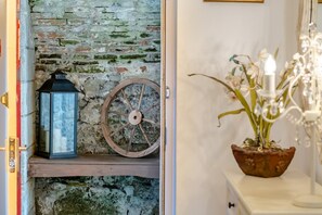 A rustic interior with a stone wall, a lantern, a wooden wheel, and a potted plant. - 3 Bed in Ventnor (oc-89972) (Niton)