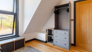 Una habitación con un ventanal grande, una puerta de madera y un banco empotrado con cajones.