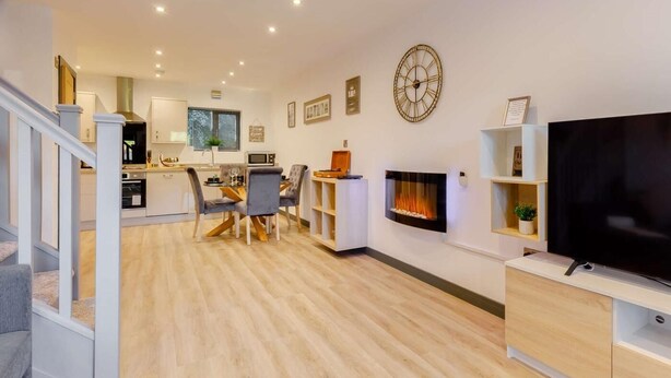 Una sala de estar moderna con chimenea, un comedor y una cocina al fondo.