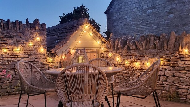 Eine Terrasse im Freien mit Steinmauern, Korbstühlen und einem Tisch.