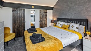 Ein Schlafzimmer mit einem Bett, einem Sessel, einem Nachttisch und einem Wandbild.