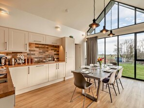 A modern kitchen with a dining area, large windows, and a view of the outdoors. - 3 Bed in Bamburgh (oc-90062) (Bamburgh)