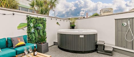 A rooftop terrace with a hot tub, a sofa, a coffee table, and a cinema sign in the background.