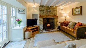 A cozy living room with a stone fireplace, a television, and a comfortable sofa. - 3 Bed in Leyburn (oc-89746) (Spennithorne)