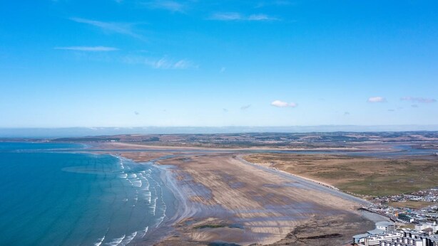 An aerial view of a coastal area with a beach, a small settlement, and a clear blue sky. - 3 Bed in Bideford (oc-89866) (Westward Ho!)