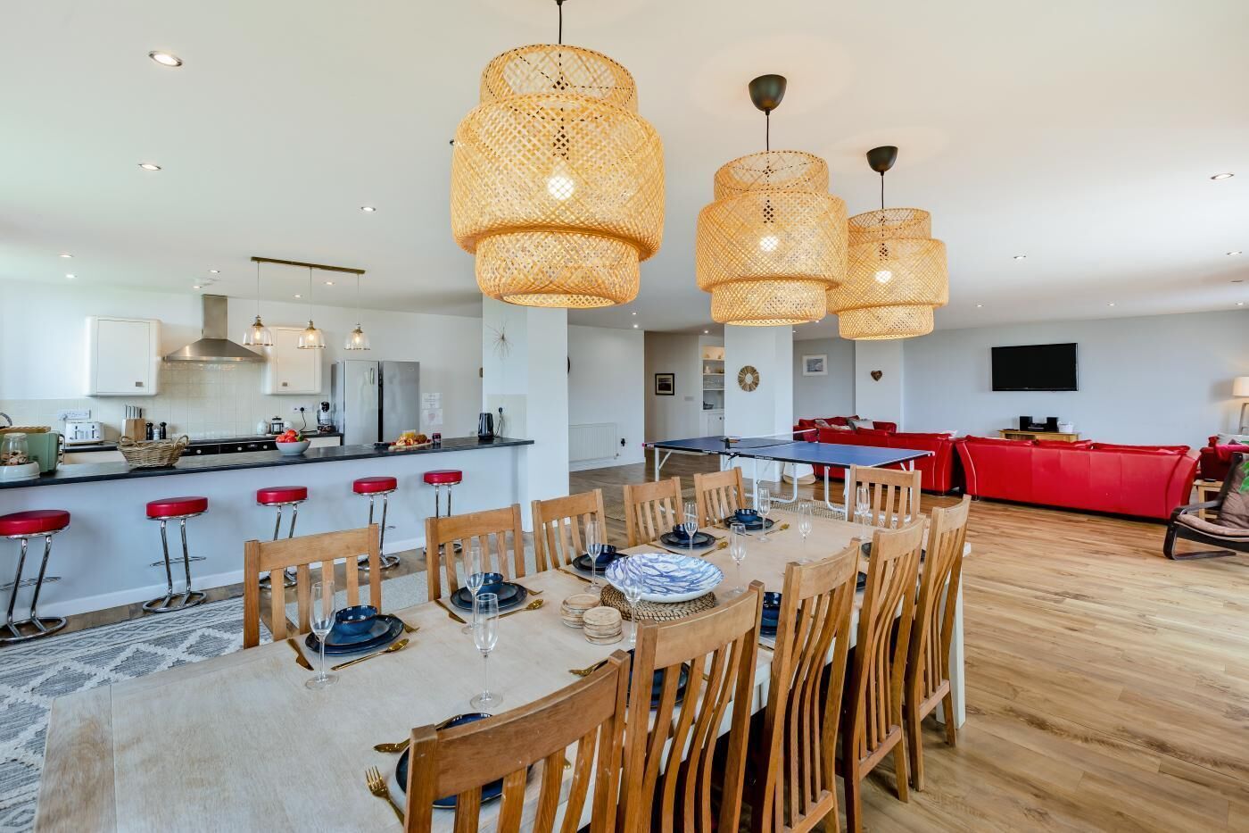 A modern kitchen with white cabinets, a central island, and a dining area with wooden chairs and a table set for six.