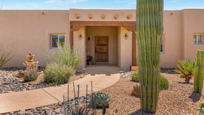 A desert-style building with a wooden door, a cactus garden, and a pathway leading to the entrance. - The Desert Preserve Pool | Desert Views | Quiet Retreat (Tucson)