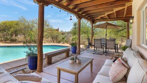 A covered outdoor patio with a pool, wooden furniture, and potted plants. - The Desert Preserve Pool | Desert Views | Quiet Retreat (Tucson)