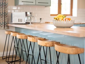 A kitchen with a light blue countertop, a bowl of fruit, and a microwave. - 3 Bed in Bideford (oc-89865) (Westward Ho!)