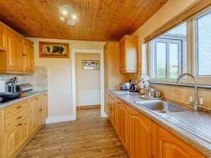 A kitchen with wooden cabinets, a granite countertop, a stainless steel sink, and a window providing natural light.