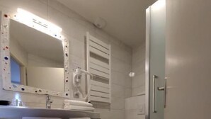 Un bagno con lavandino, specchio, portasciuga, WC e zona doccia.