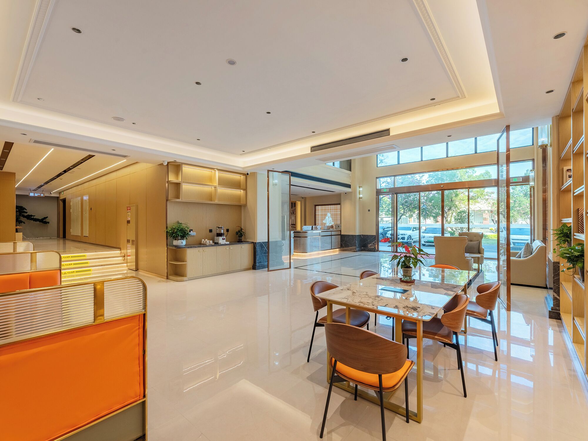 A modern hotel lobby with a reception desk, seating area, and a large window offering a view of the outdoors.