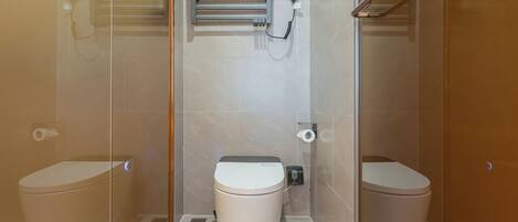 Un baño moderno con cabina de ducha de vidrio, dos inodoros y un perchero para toallas.