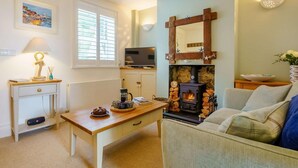 Una sala de estar acogedora con chimenea, televisor, sofá y una mesa con lámpara y objetos decorativos.
