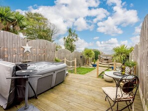 A hot tub on a wooden deck, surrounded by a wooden fence, with a star decoration and string lights. - 2 Bed in Ventnor (oc-90147) (Ventnor)