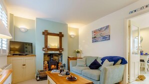 Una sala de estar acogedora con chimenea, sofá, mesa de centro y televisión.