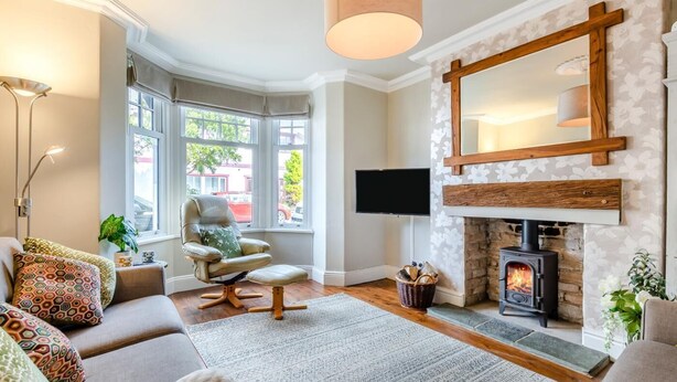 A cozy living room with a fireplace, comfortable seating, a flat-screen TV, and large windows. - 3 Bed in Keswick (oc-89526) (Keswick)